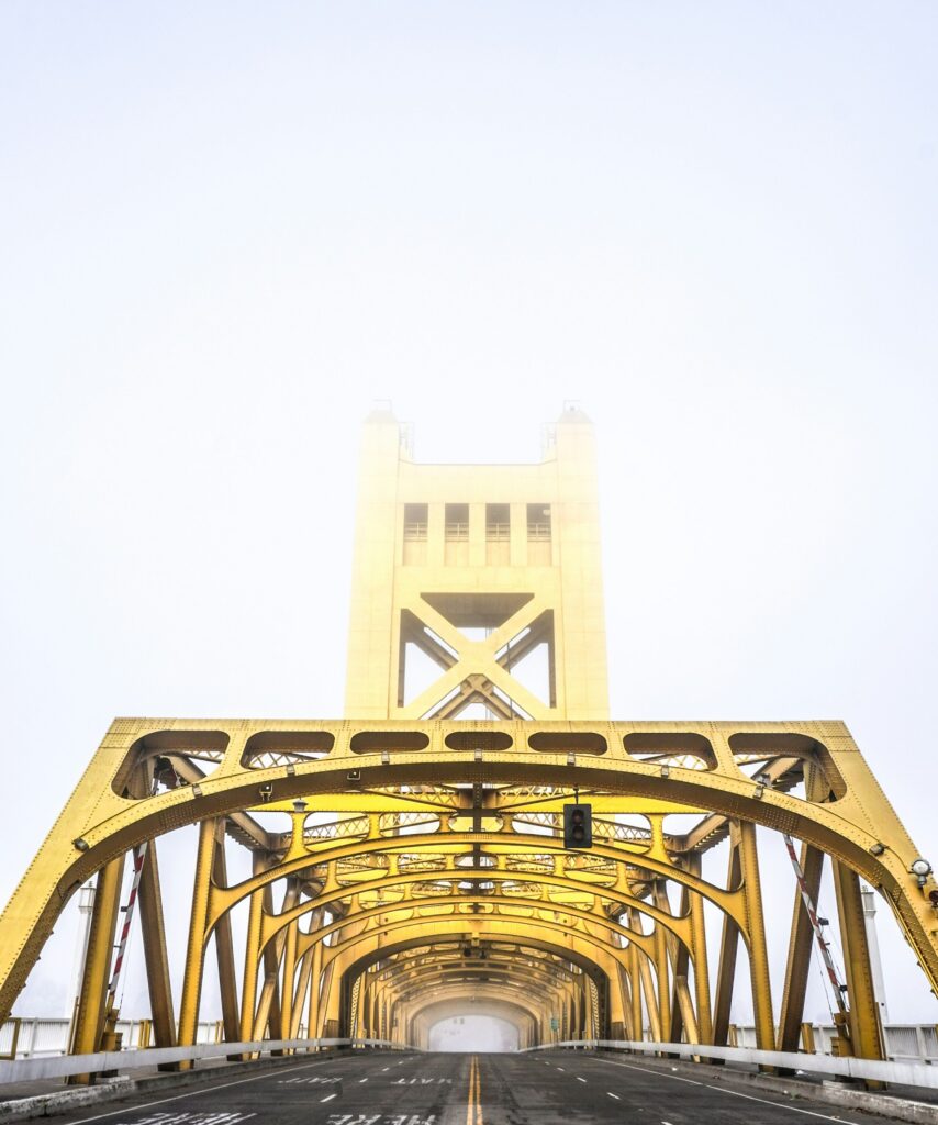 The golden Tower Bridge entering into Sacramento, California during a foggy morning